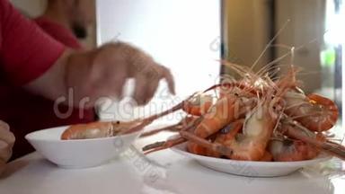 一家<strong>海鲜店</strong>里的人把煮好的虾放在盘子里。 拍摄特写。